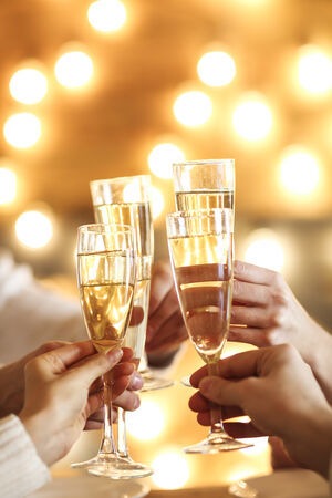 Champagne glasses in hands on golden background. Party and celebration concept